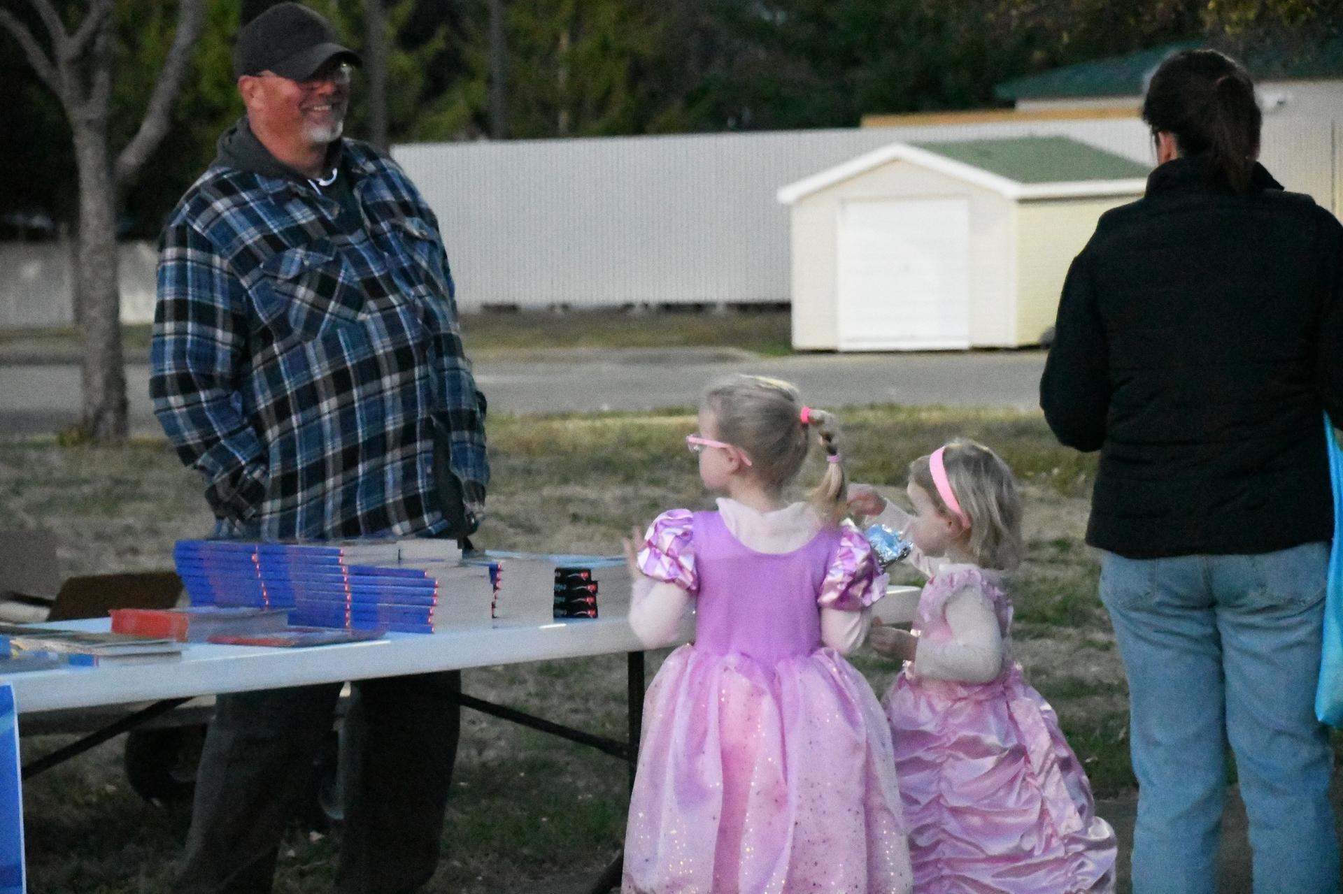 Picture of WES Trunk-or-Treat event; staff handing out books to students in costumes